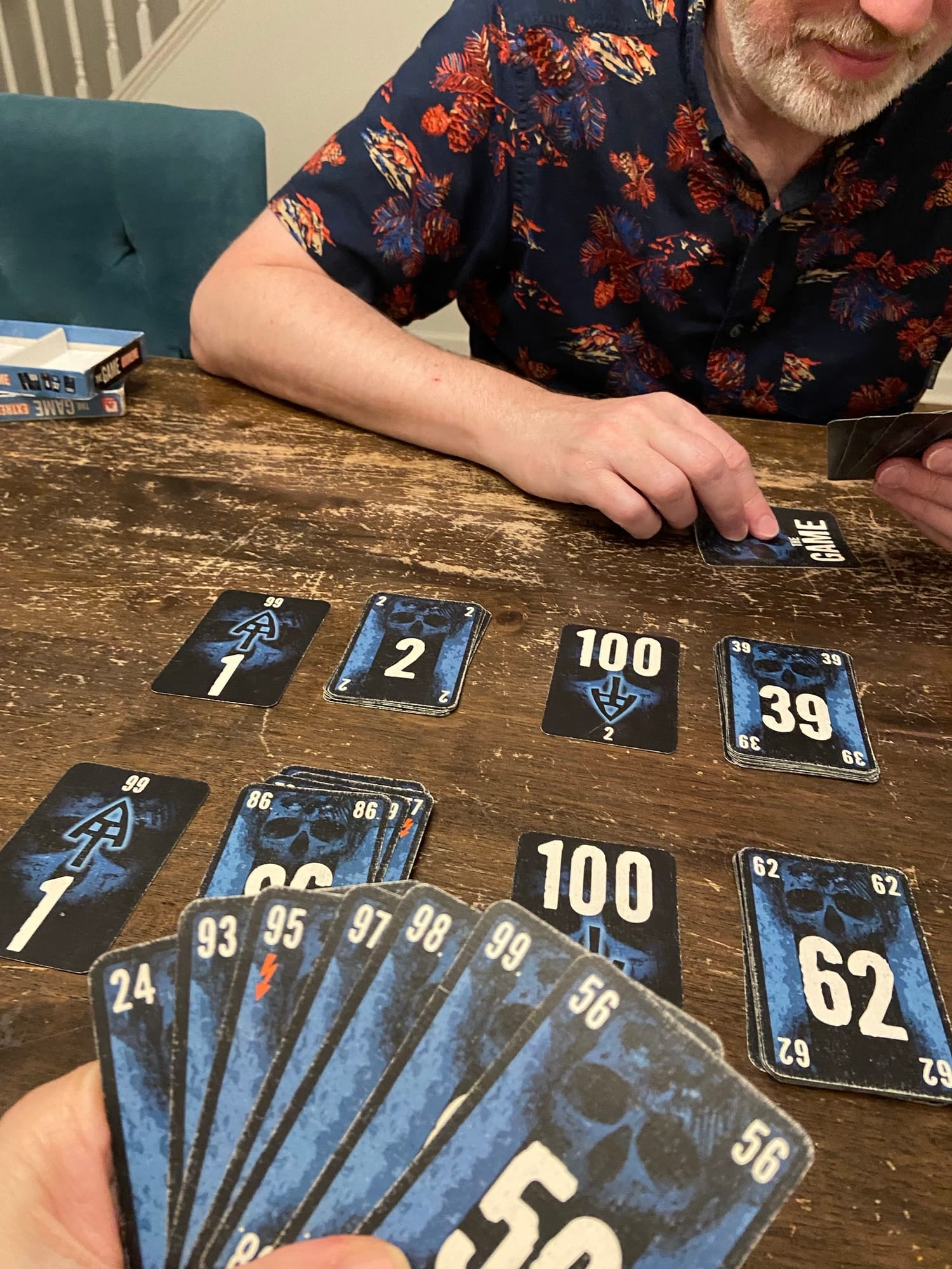 A hand of cards is in the foreground showing the numbers 24, 56, 93, 95, 97, 98, and 99; four discard piles are visible on the table.