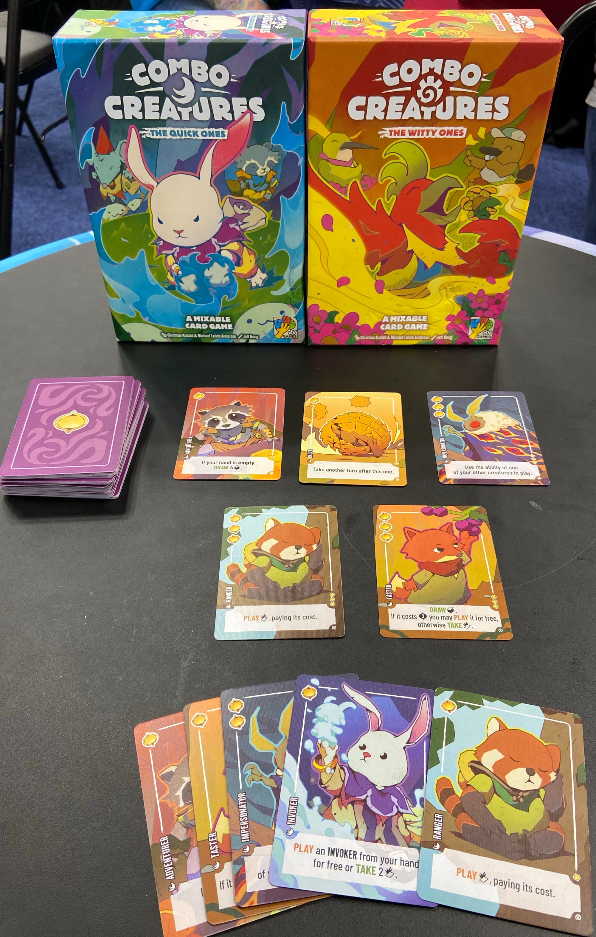 The boxes for Combo Creatures: The Quick Ones and Combo Creatures: The Witty Ones stand on a table behind some of the included cards. Sample card powers include "Take another turn after this one", "If your hand is empty, draw 4 cards." and "Play an INVOKER from your hand for free or take 2 cards from the market."