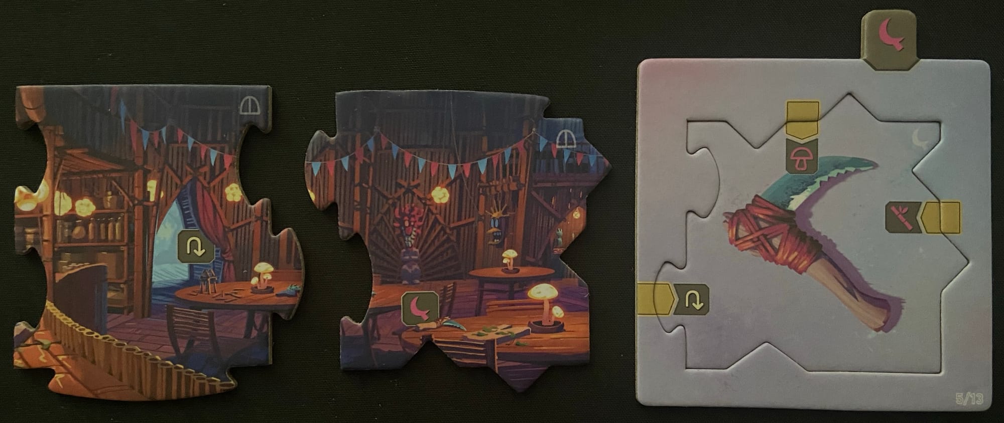 The two puzzle pieces are now punched out and next to another tile in a sleeve, this one showing a scythe-like tool.