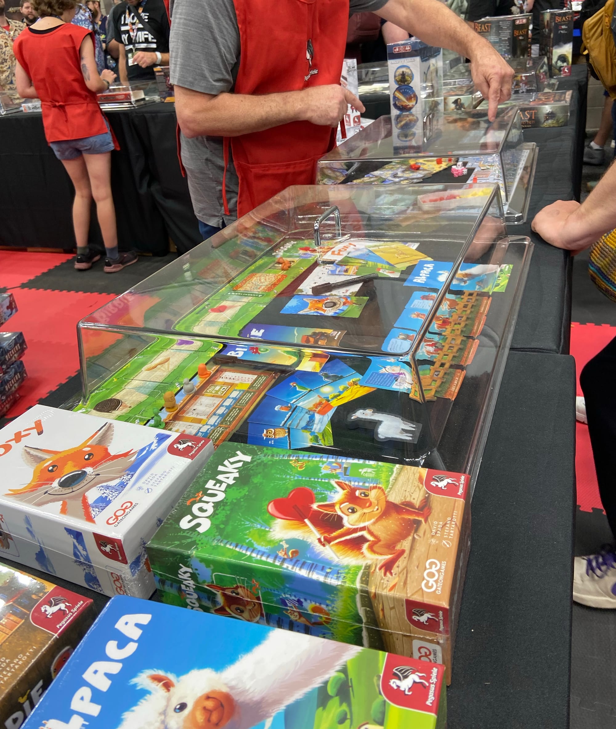 An array of games from Pegasus Spiele are laid out on tables, with plastic covers on top of many of the game components.