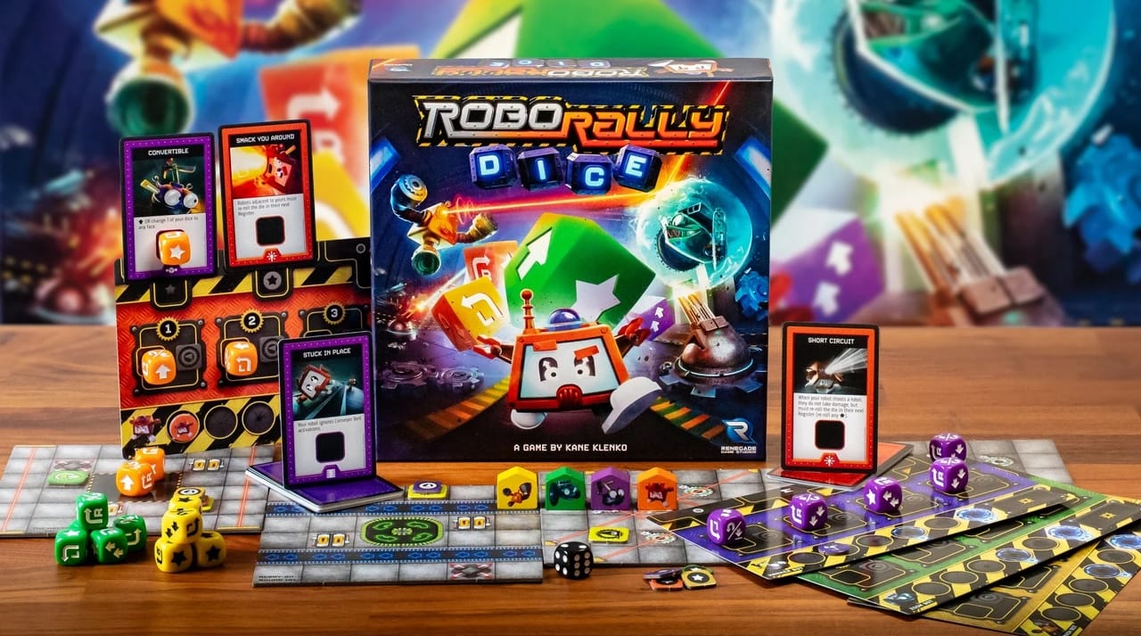 The Robo Rally Dice game box sits on a table next to game boards, individual player boards, dice, and upgrade cards.