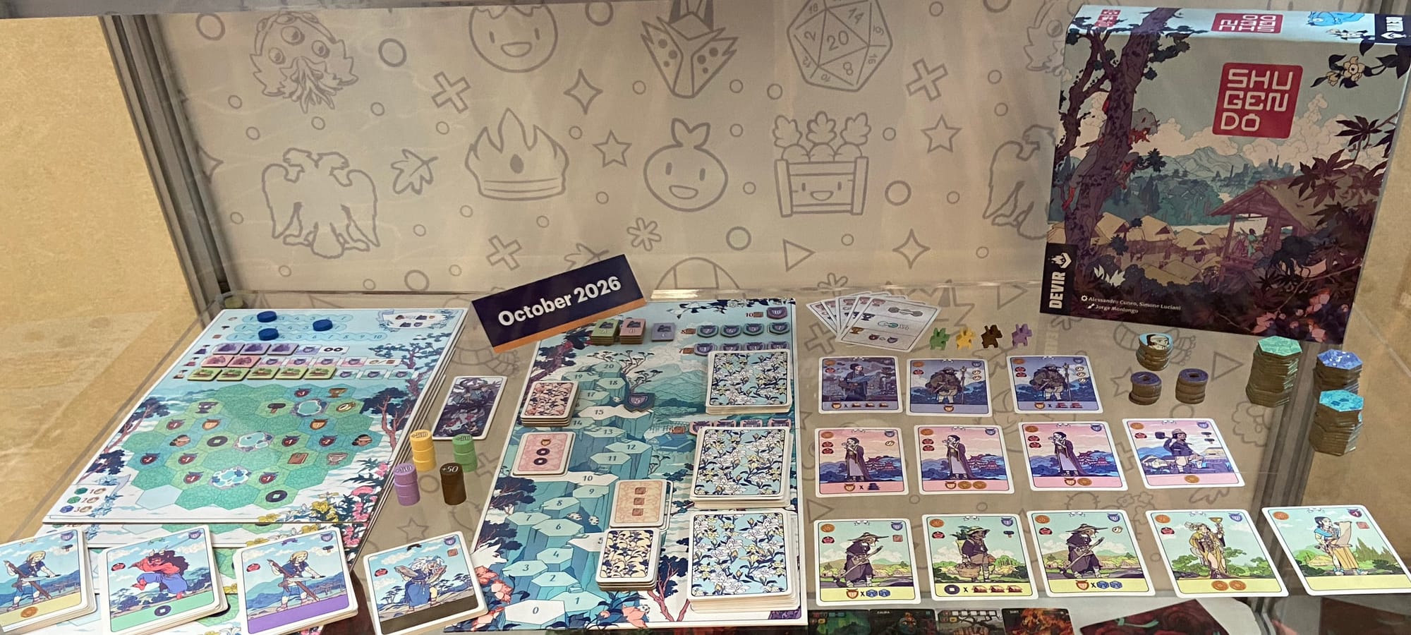 The Shugendo box features a village, and the display case features individual game boards where players will place tiles, as well as decks of cards that display villagers.