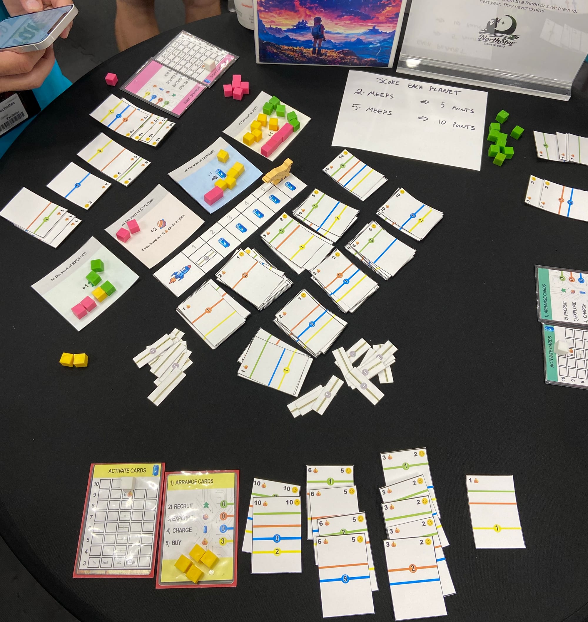 Lots of piles of paper are still on the table, but players now have rows of cards in front of themselves so that they can tally the points on those cards.