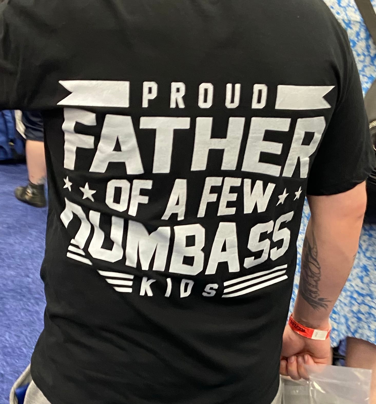 The back of a T-shirt reads: "Proud Father of a Few Dumbass Kids"