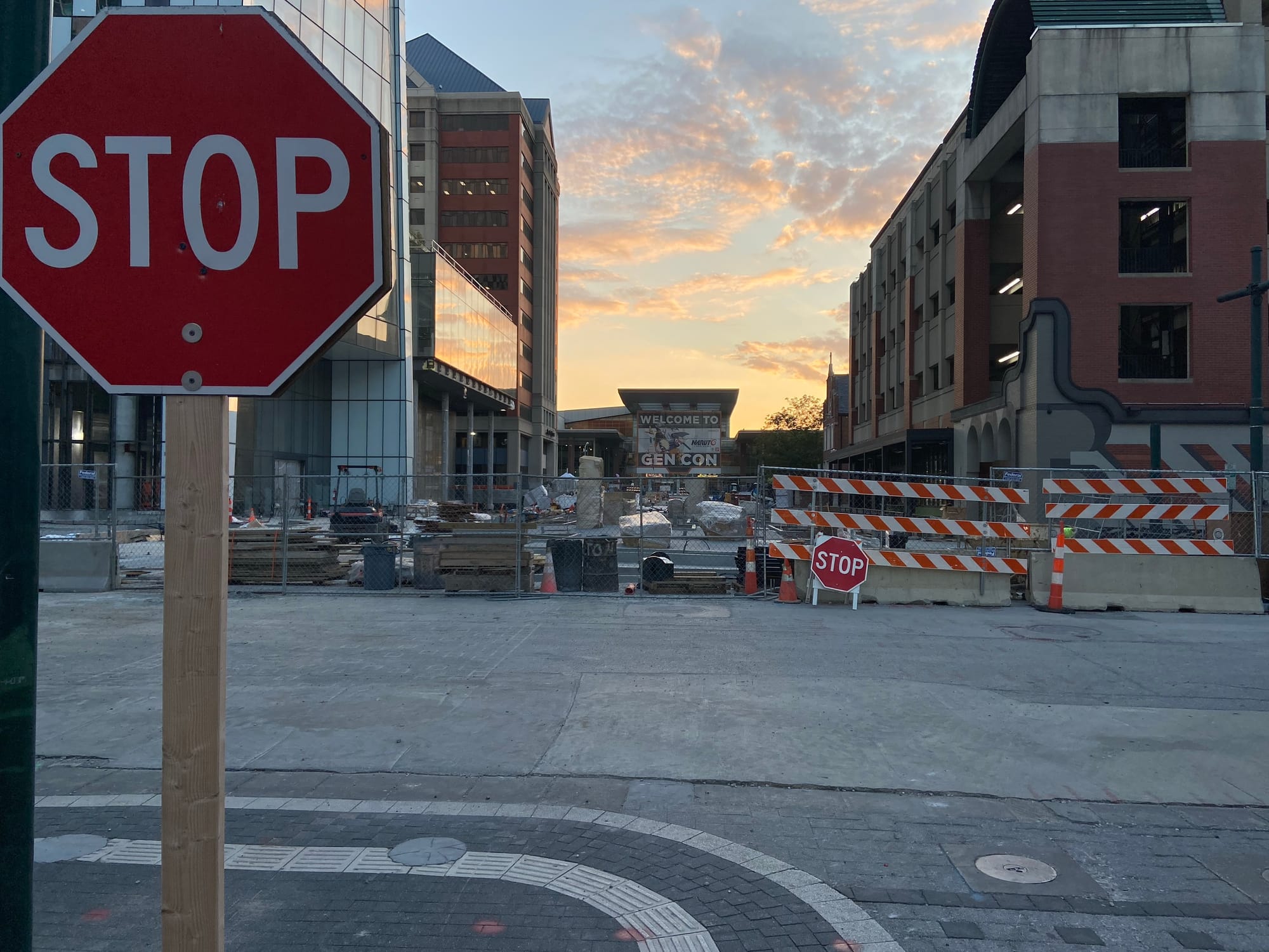 A STOP sign is close to camera on the left-side of the image. Construction has closed the street leading to the Indiana Convention Center, which bears a sign reading "Welcome to Gen Con".