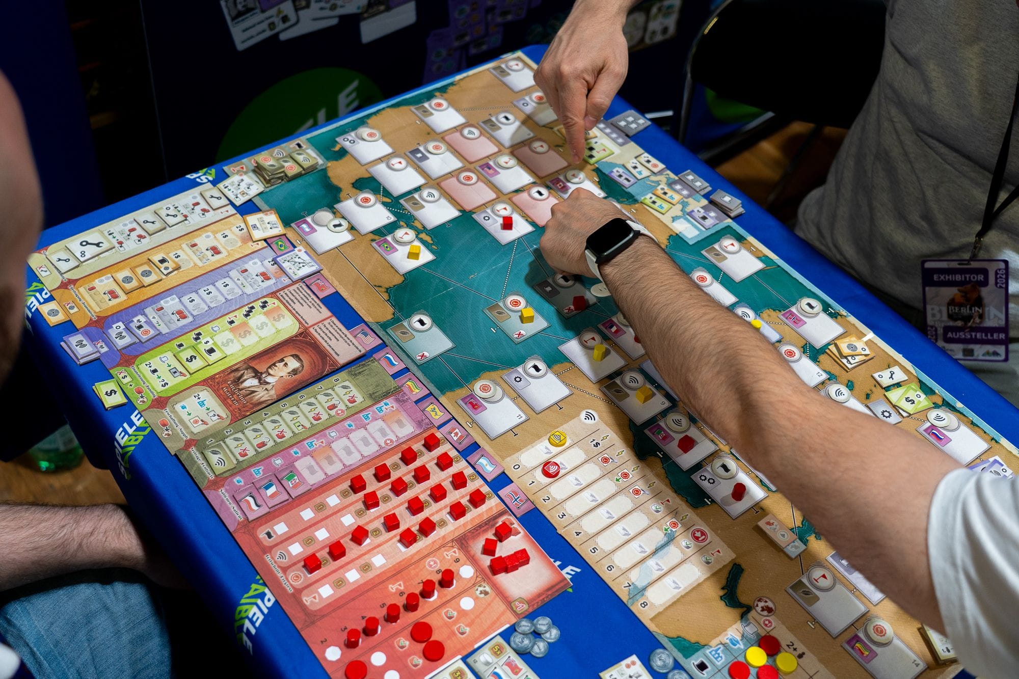 The image shows a map of North America and Europe covered by location spaces, icons, and cubes. A player's two game boards are visible, with eight columns in which to track information.