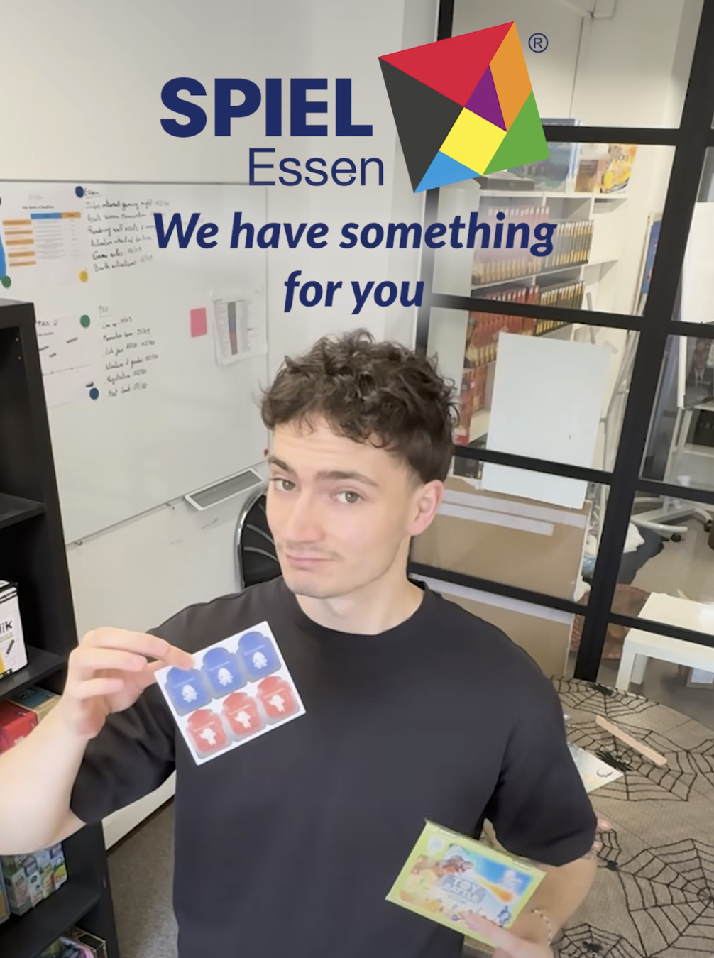 A man holds a piece of cardboard that features three tokens for each player in the game Toy Battle.