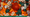 Inside a box with a red background, you see large & small dice, wooden lower-case Gs, silver pigs, golden bananas, large & small orange traffic cones, and large & small green wooden figures.
