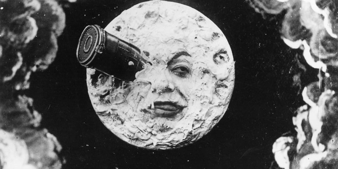 An image of the moon with a partially obscured human face whose right eye has been struck by a bullet-shaped lander.
