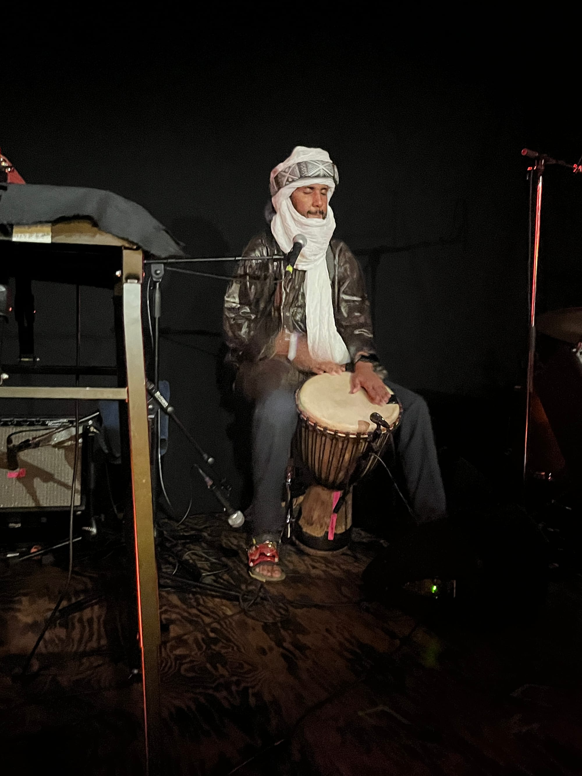 Farid Hamidou on djembe in a white headdress with a black-and-white pattern in front.