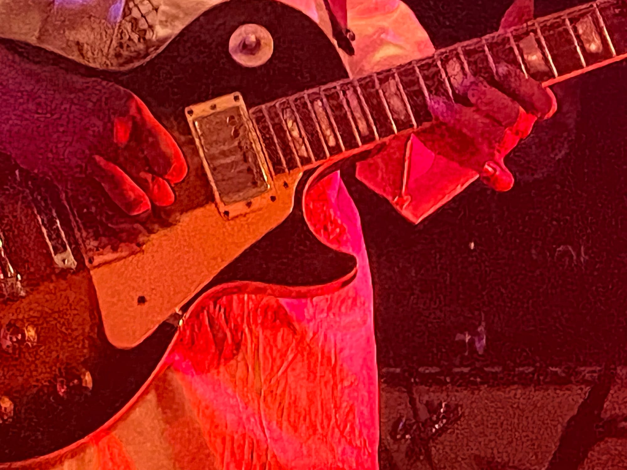 A grainy closeup of both of Ousmane’s hands as he plays his electric guitar.