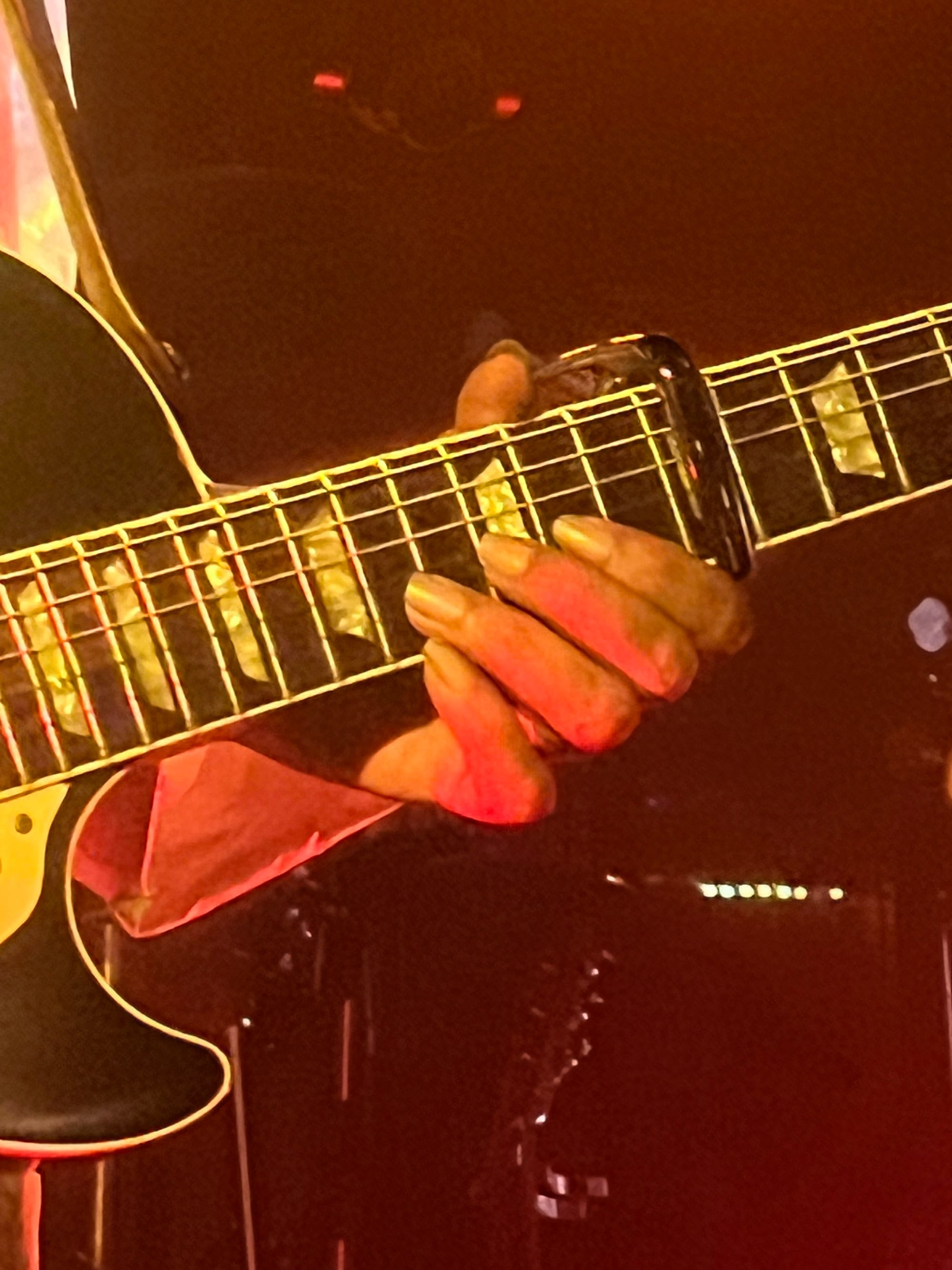 A closeup of Ousmane’s left hand on the neck of his electric guitar.