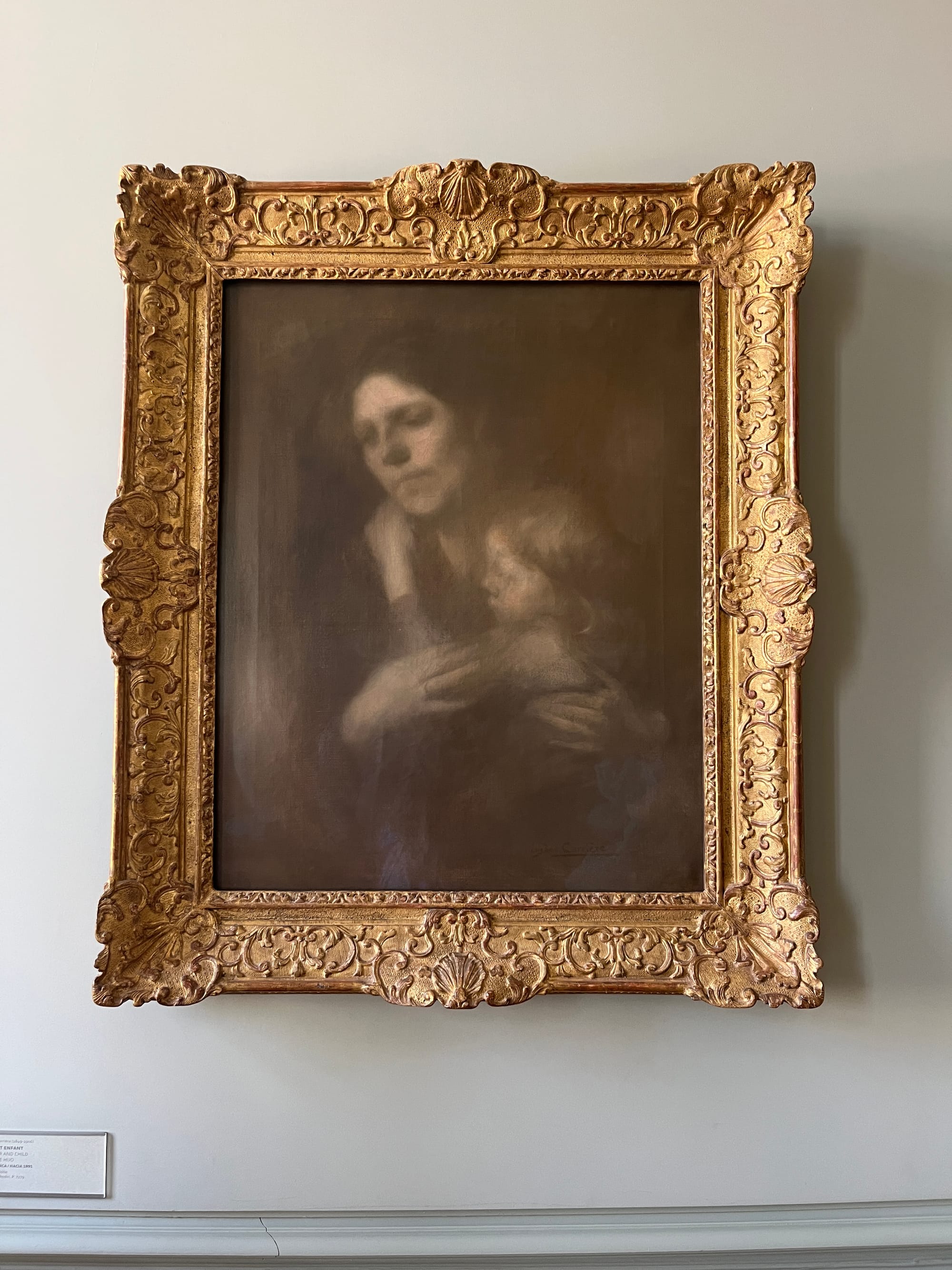 A painting in a black-brown-and-gray nineteenth-century photographic style of a mother and child embracing.