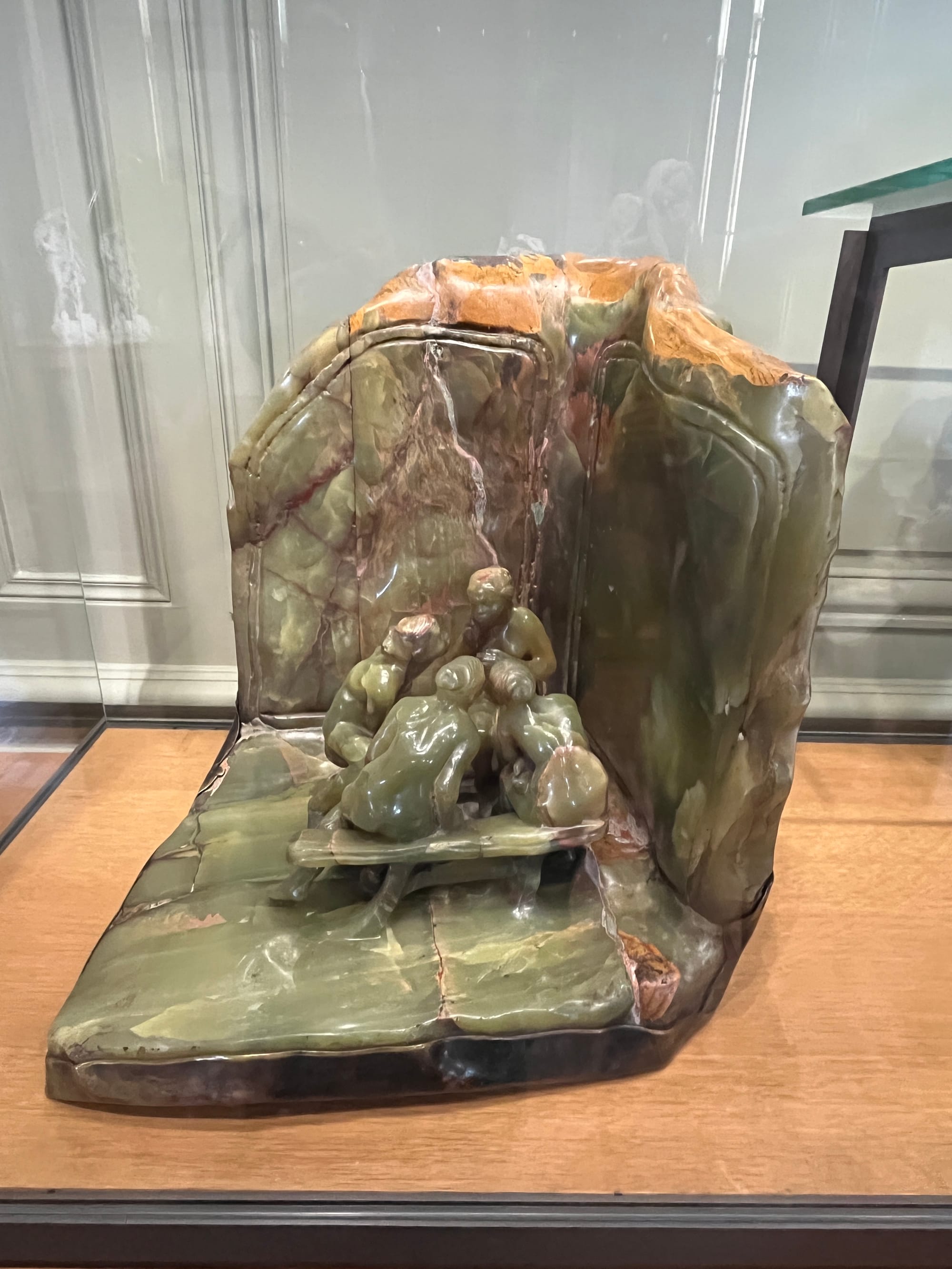 This sculpture in onyx and bronze depicts four women sitting and chatting around a table in the corner of a room.