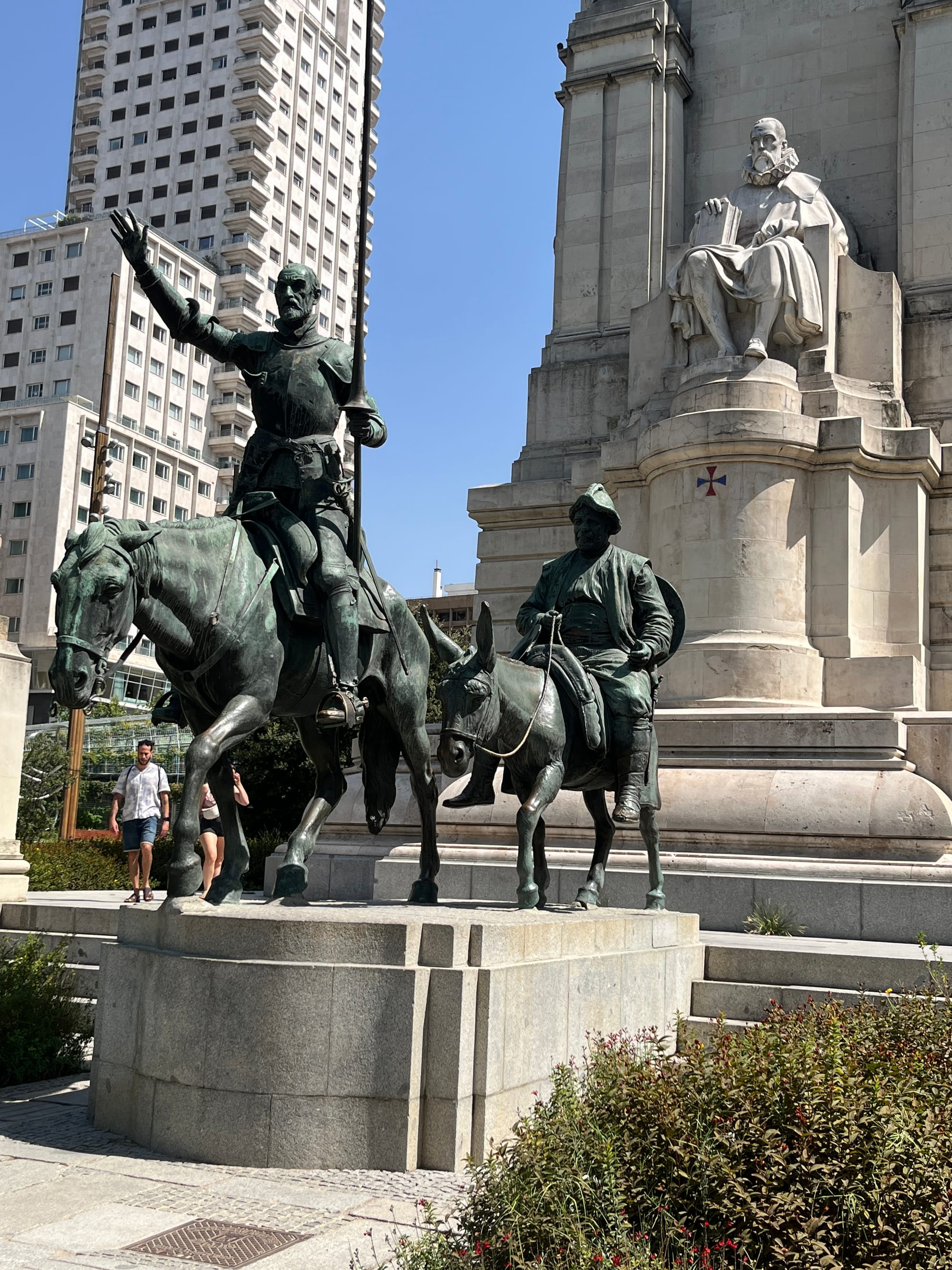 On the left, a bronze statue of Don Quijote; in the middle, one of Sancho Panza; behind them, a stone sculpture of Cervantes on a pedestal.