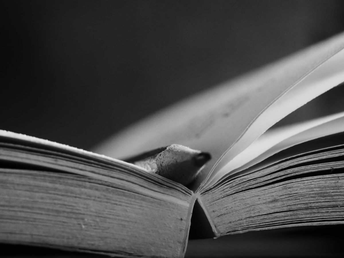 black and white photo of an open sketch book with a pencil nestled in the spine