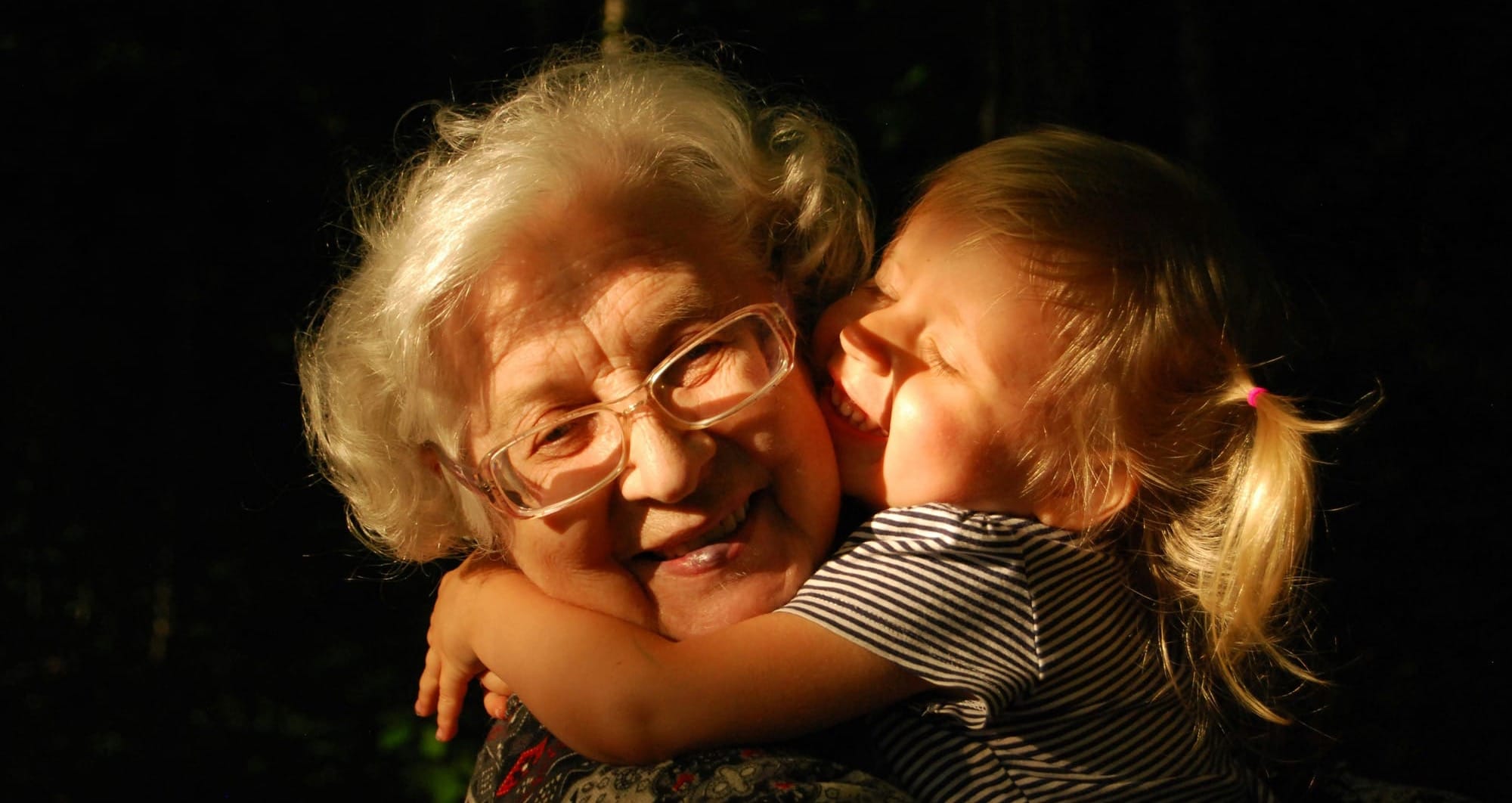 Older woman and young child enjoy a hug.