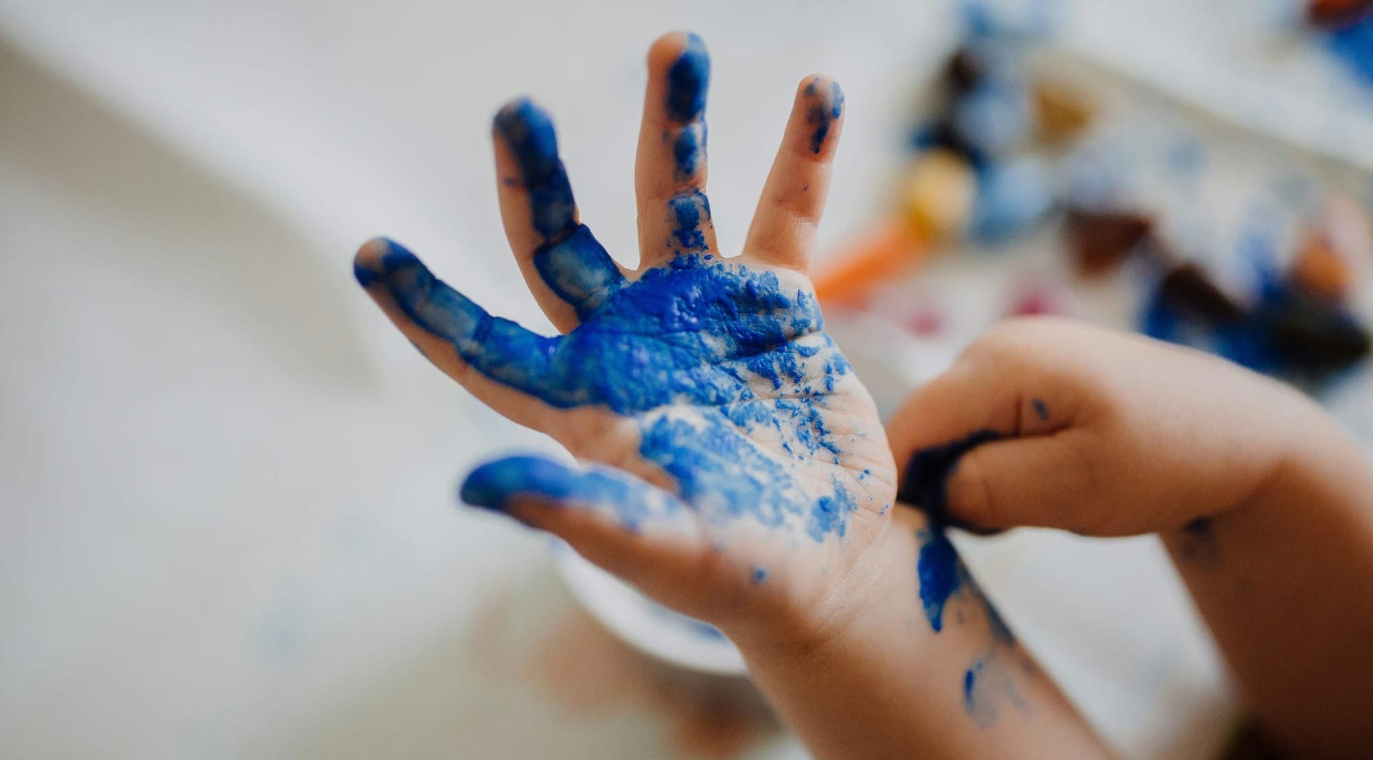 A child has explored by painting their hand blue.