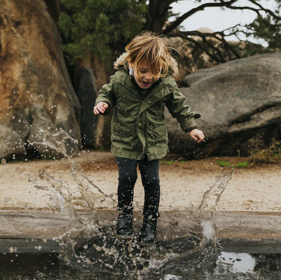 A child enjoys making a big splash in a puddle.