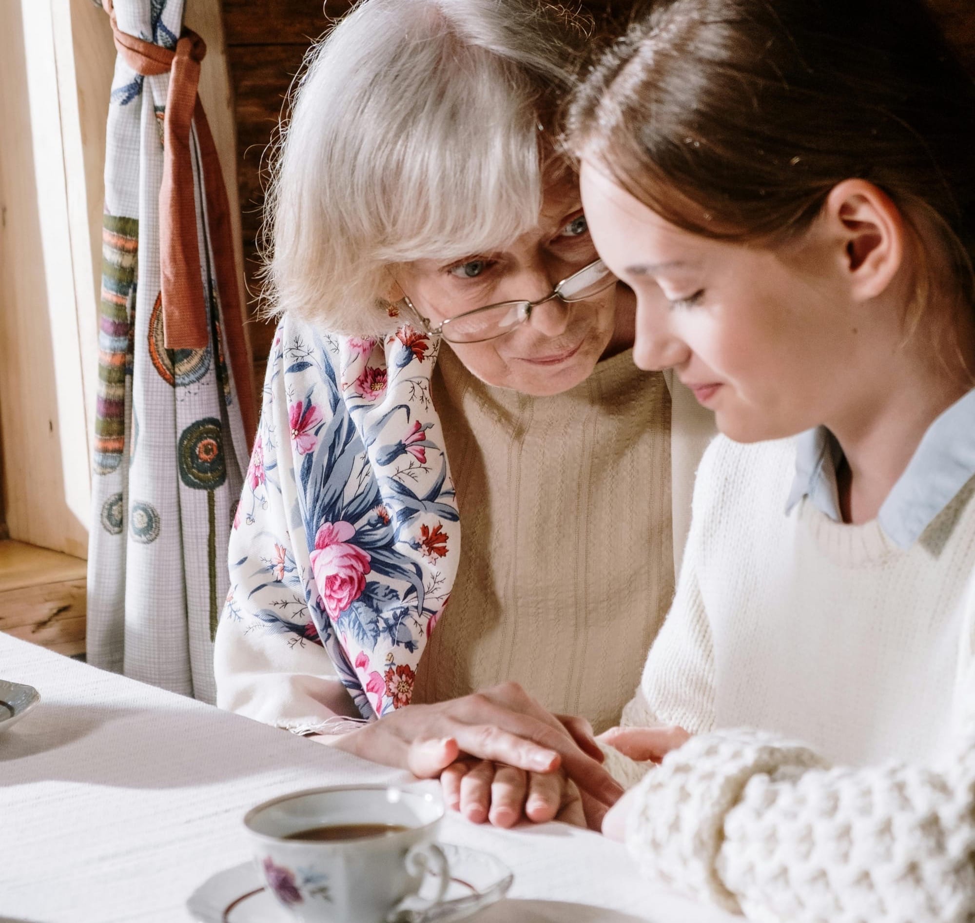 A grandmother shares a moment with her slightly smiling teenage granddaughter.
