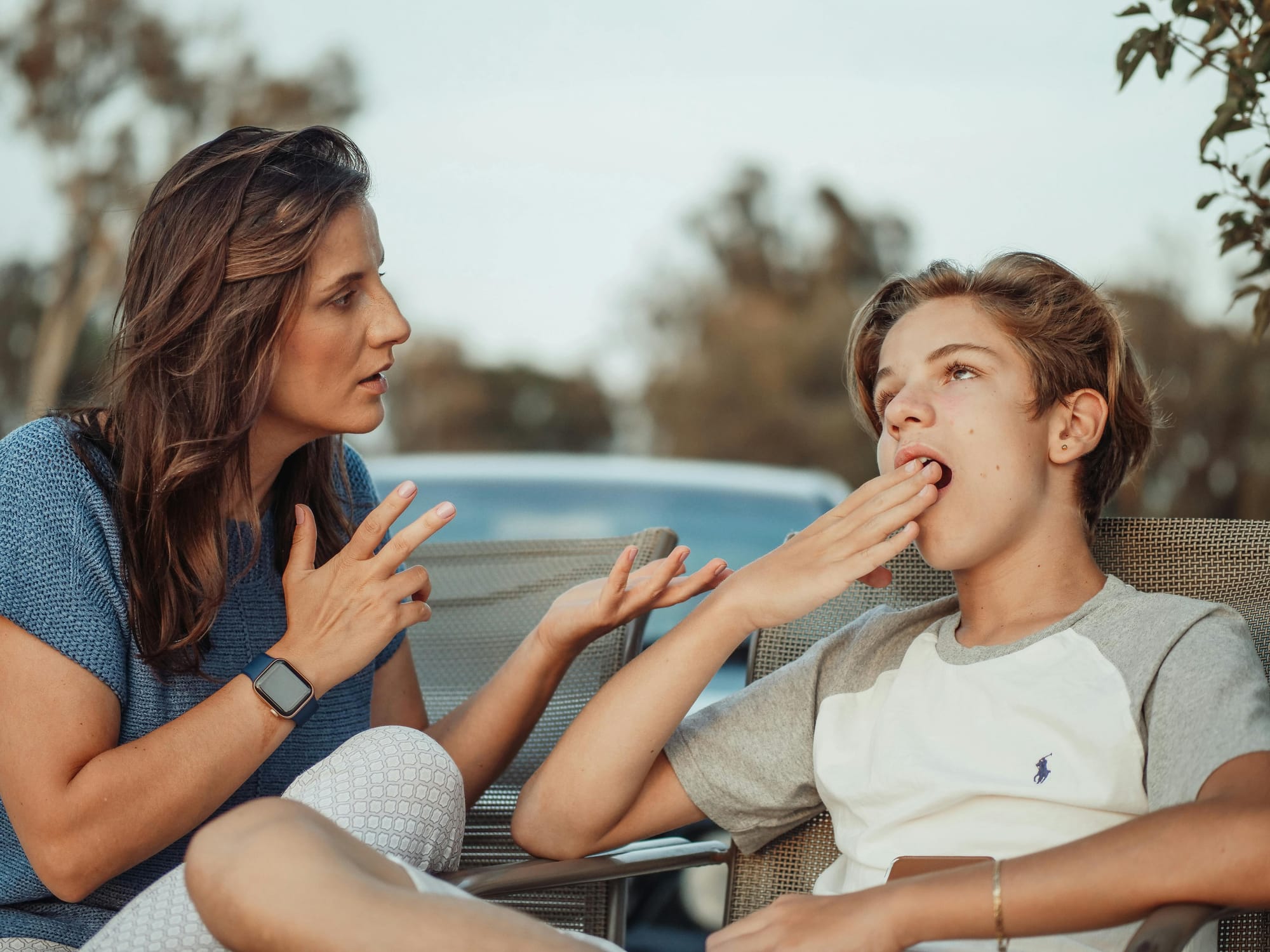 A woman appears to be explaining something to a young teen, who appears bored.