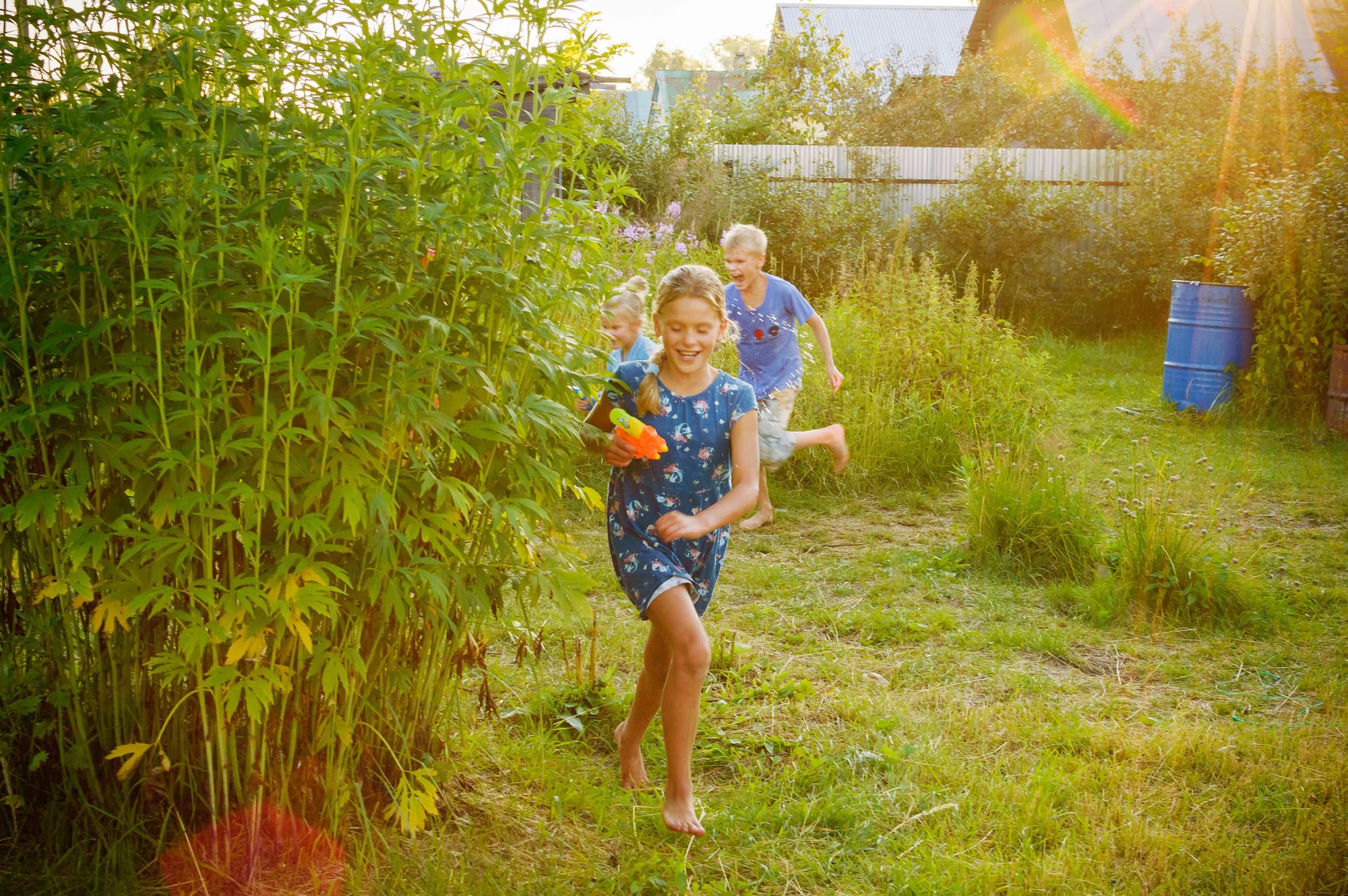 Barefoot kids enjoying outdoor play with a squirt gun. 