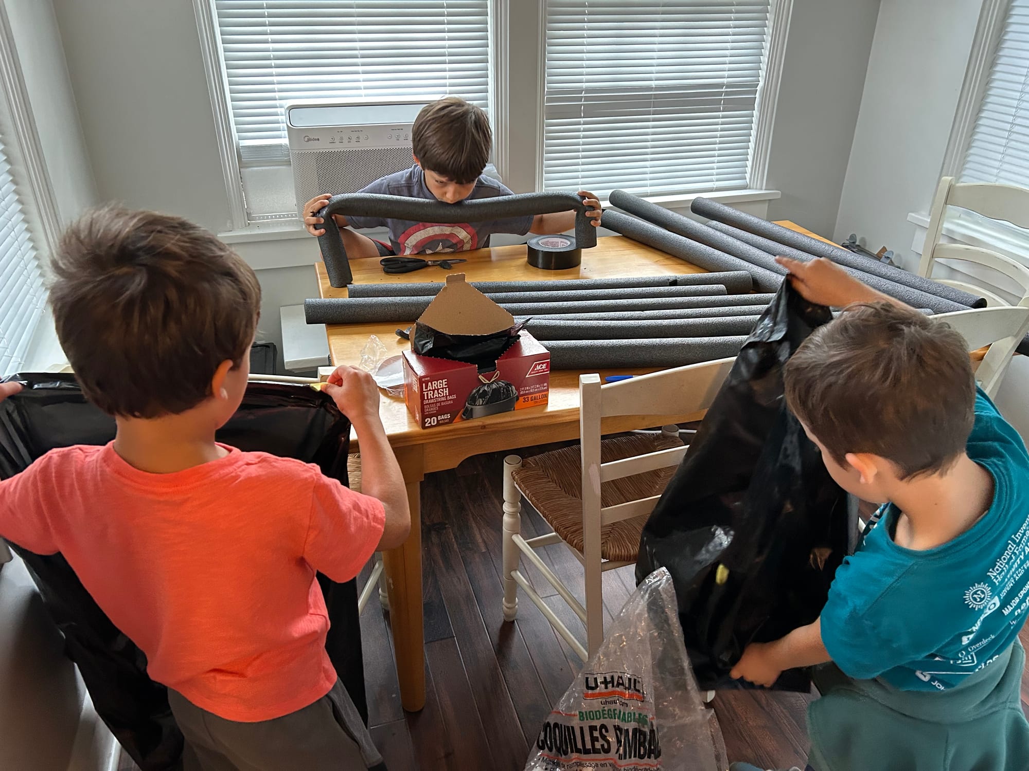 Two boys work on Step 6 of the spider craft instructions, scooping packing peanuts into plastic bags.