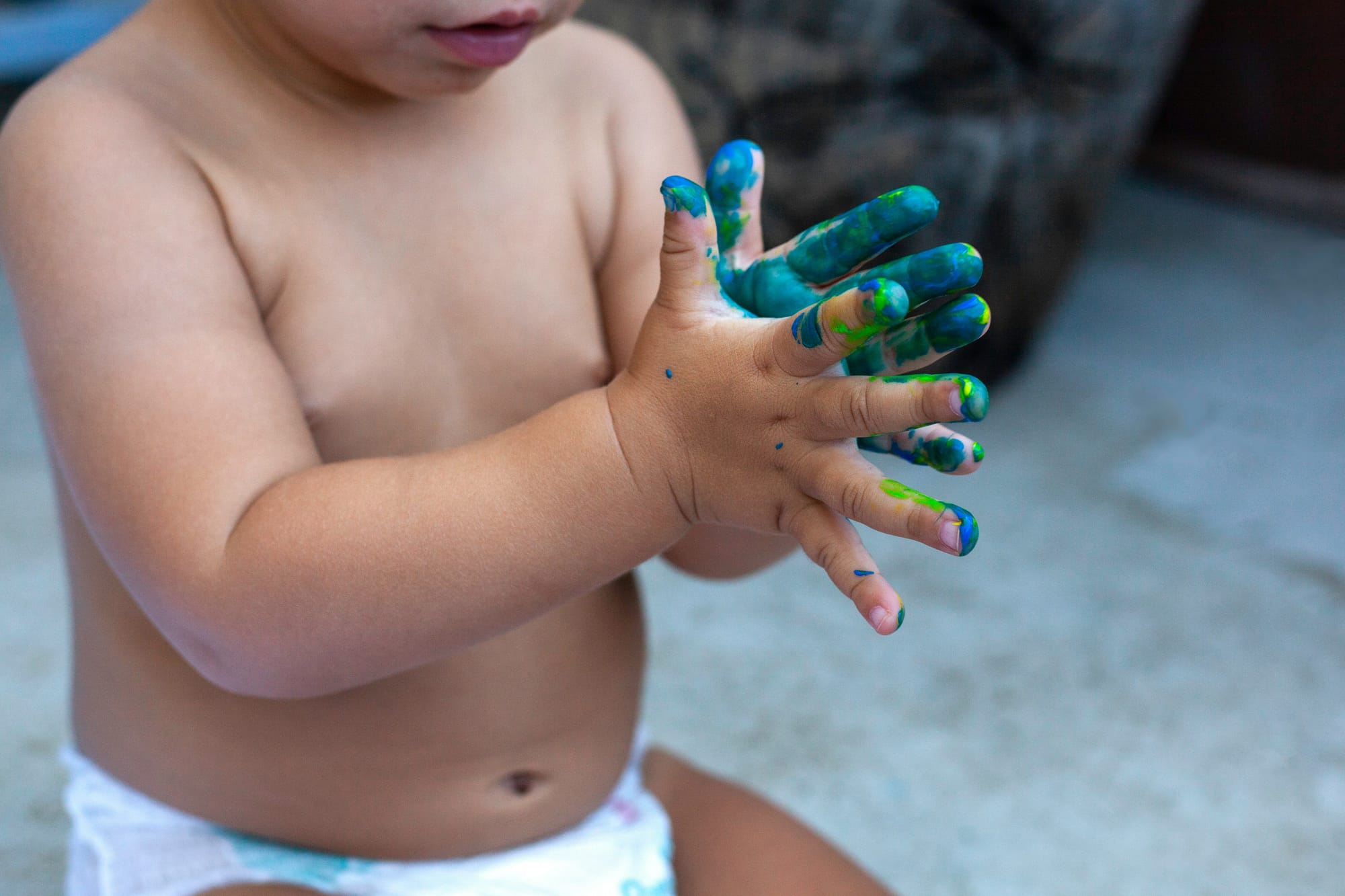 A toddler with hands very messy from fingerprint. 