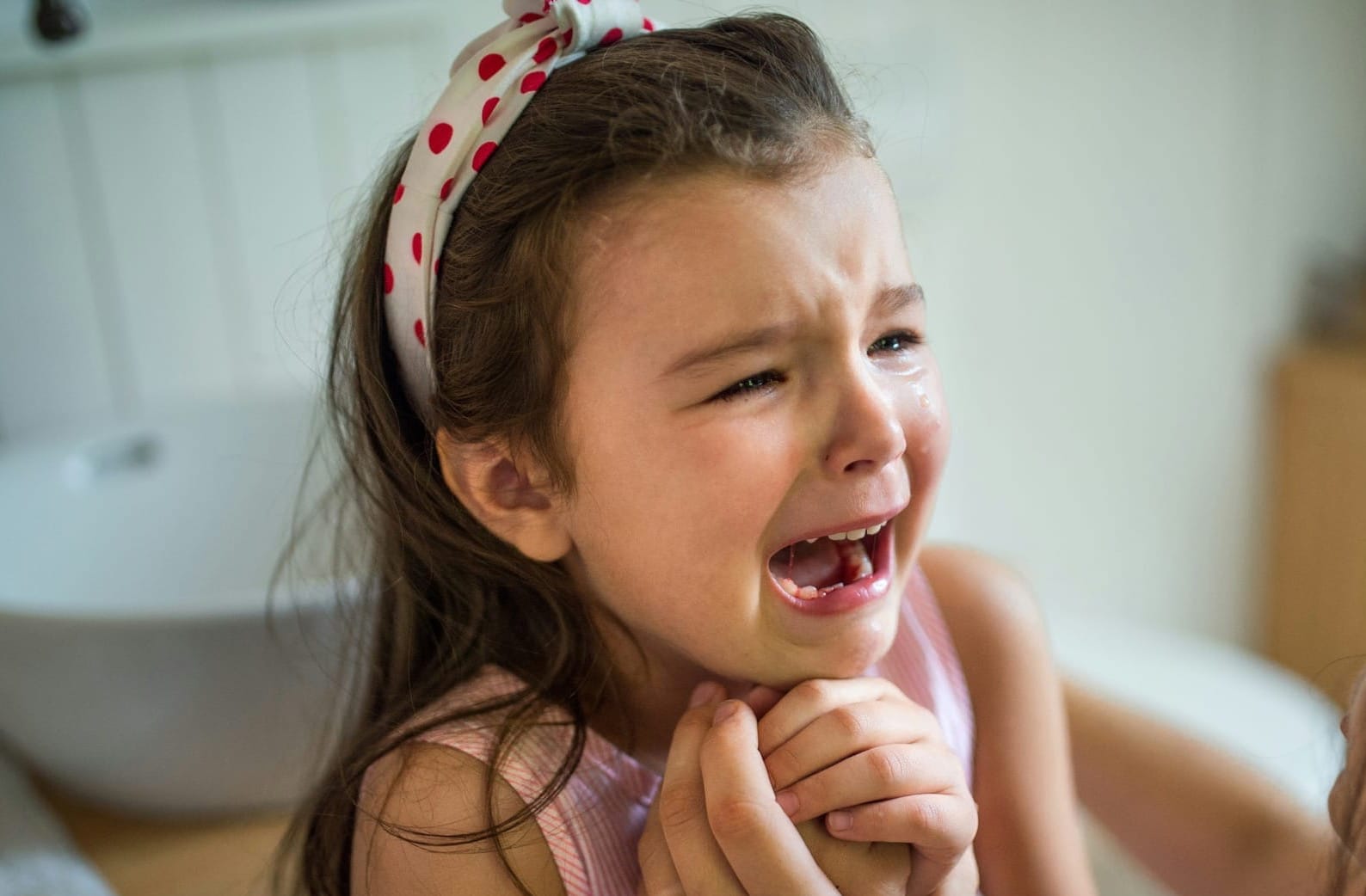 A young girl cries, making eye contact with her caregiver.