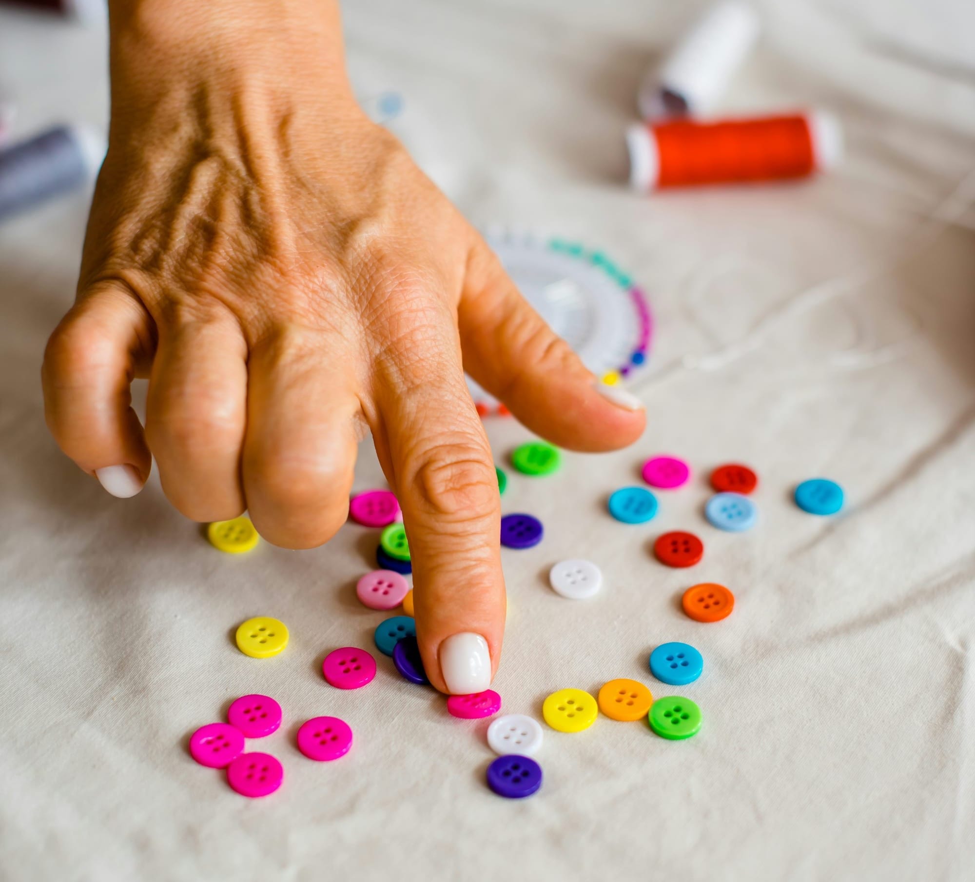 A hand sorting brightly colored buttons. 