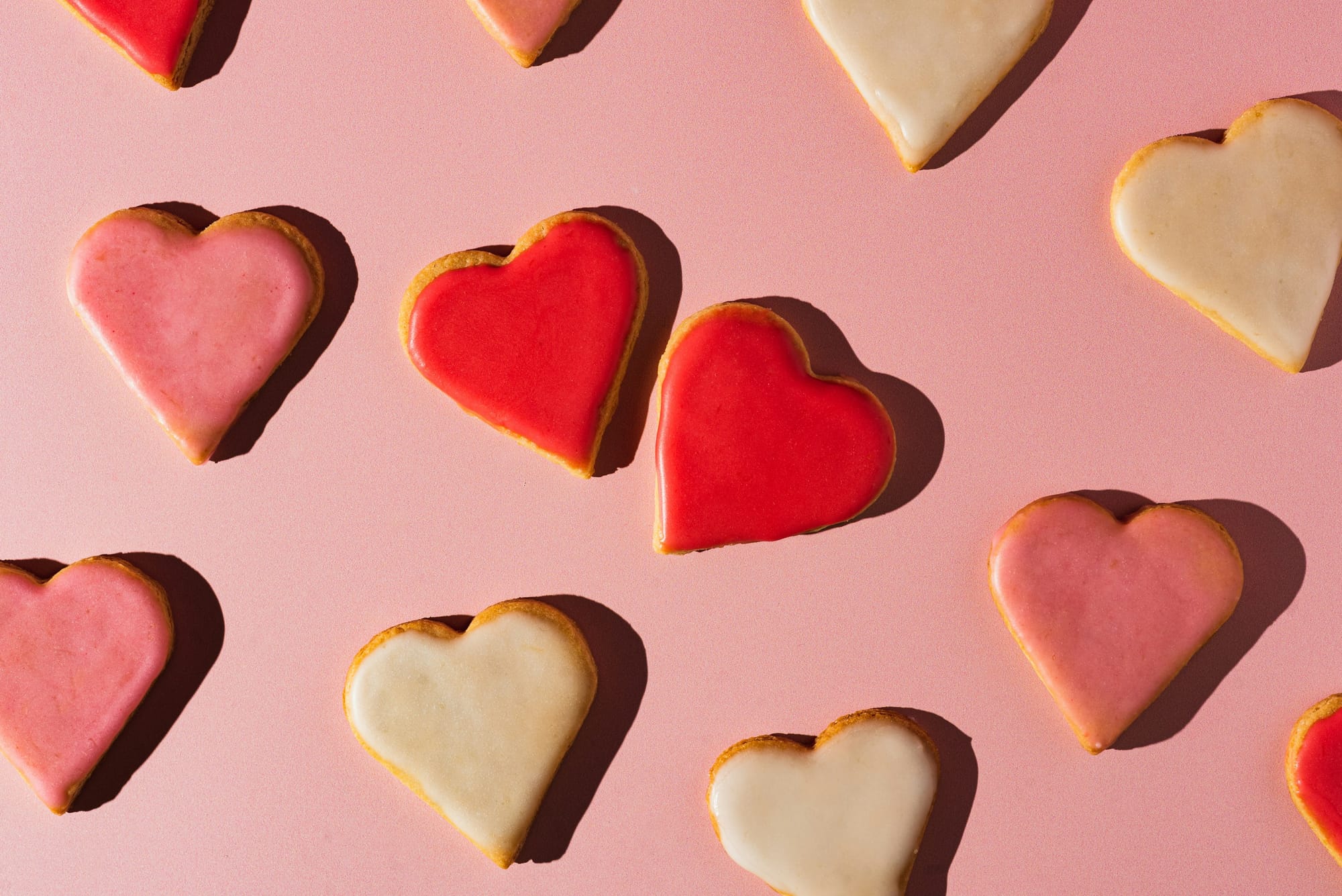 Heart-shaped frosted cookies with red, pink, and white icing.