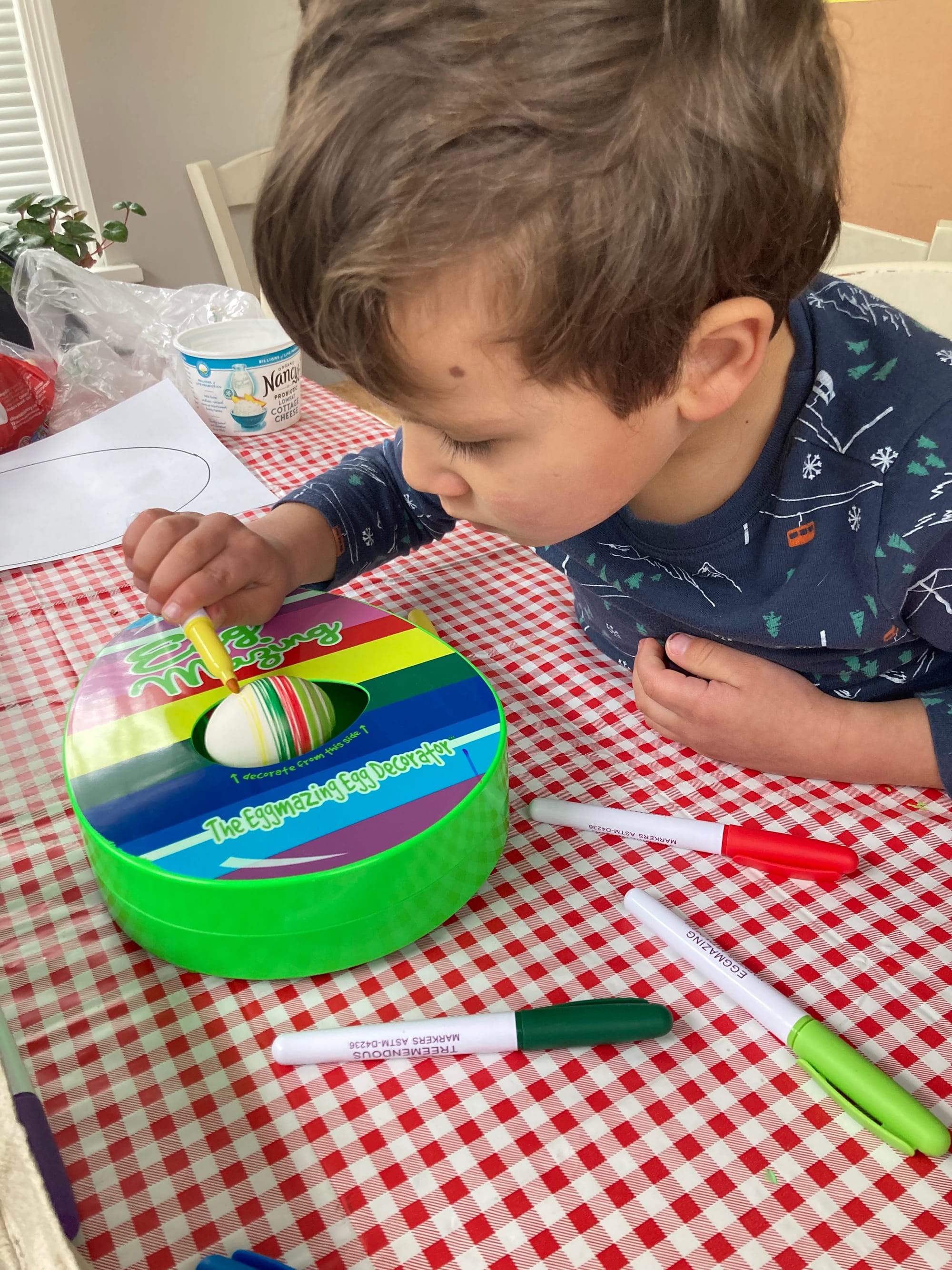 A preschooler uses an Eggmazing Egg Decorating machine. 