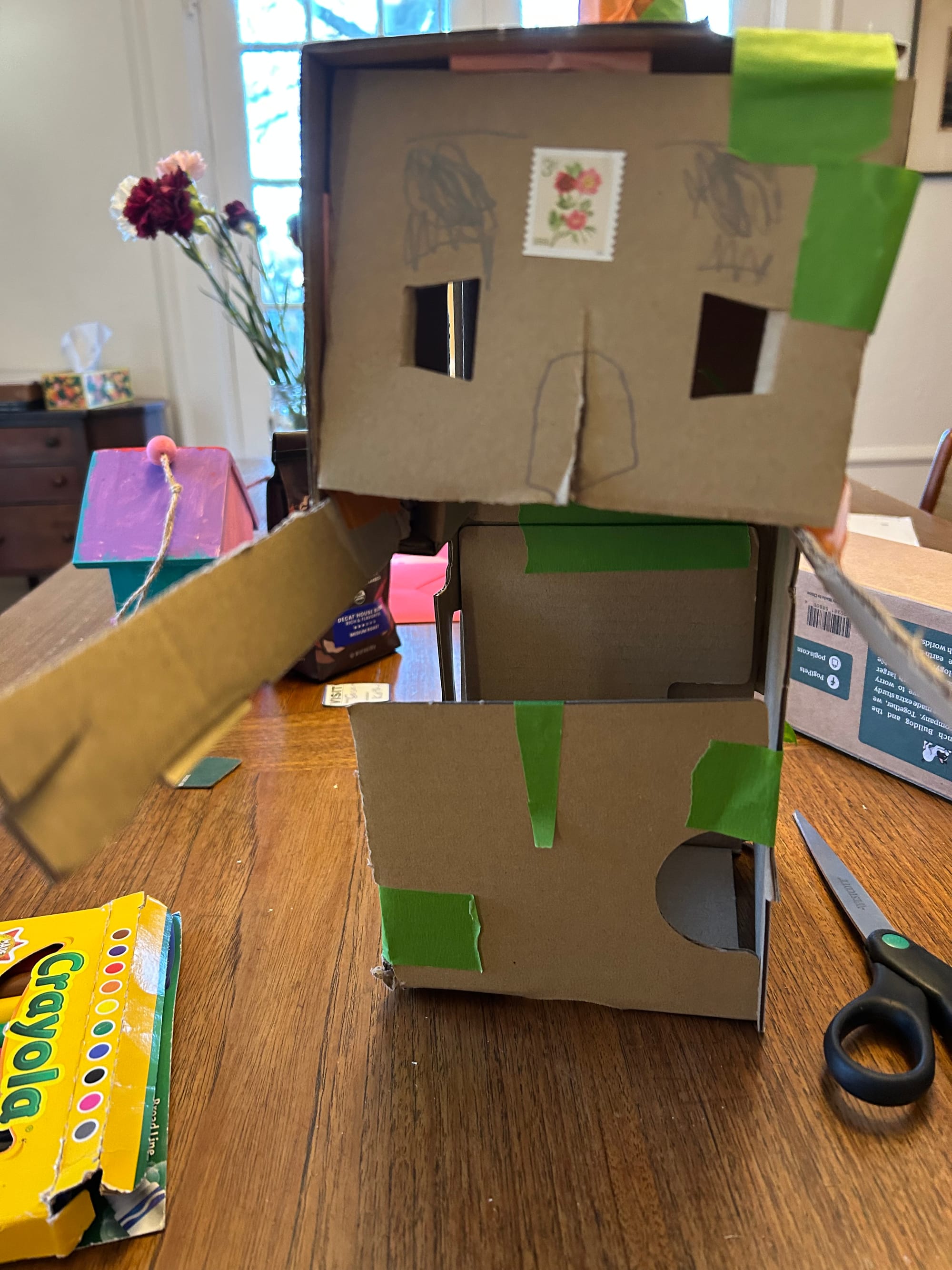 A cardboard robot, very roughly crafted with lots of green masking tape. 