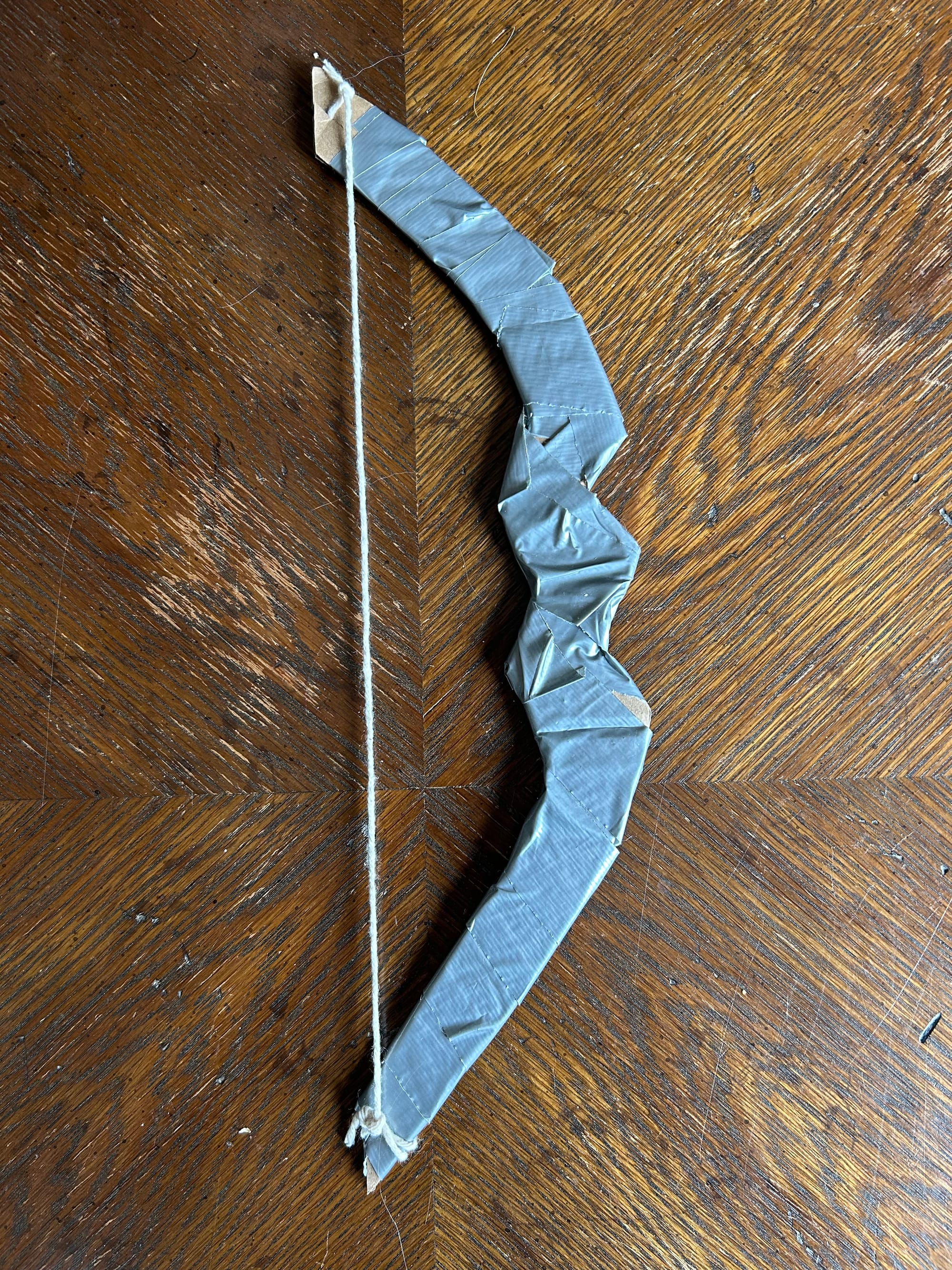 A bow crafted of duct-tape covered cardboard and cotton string. 