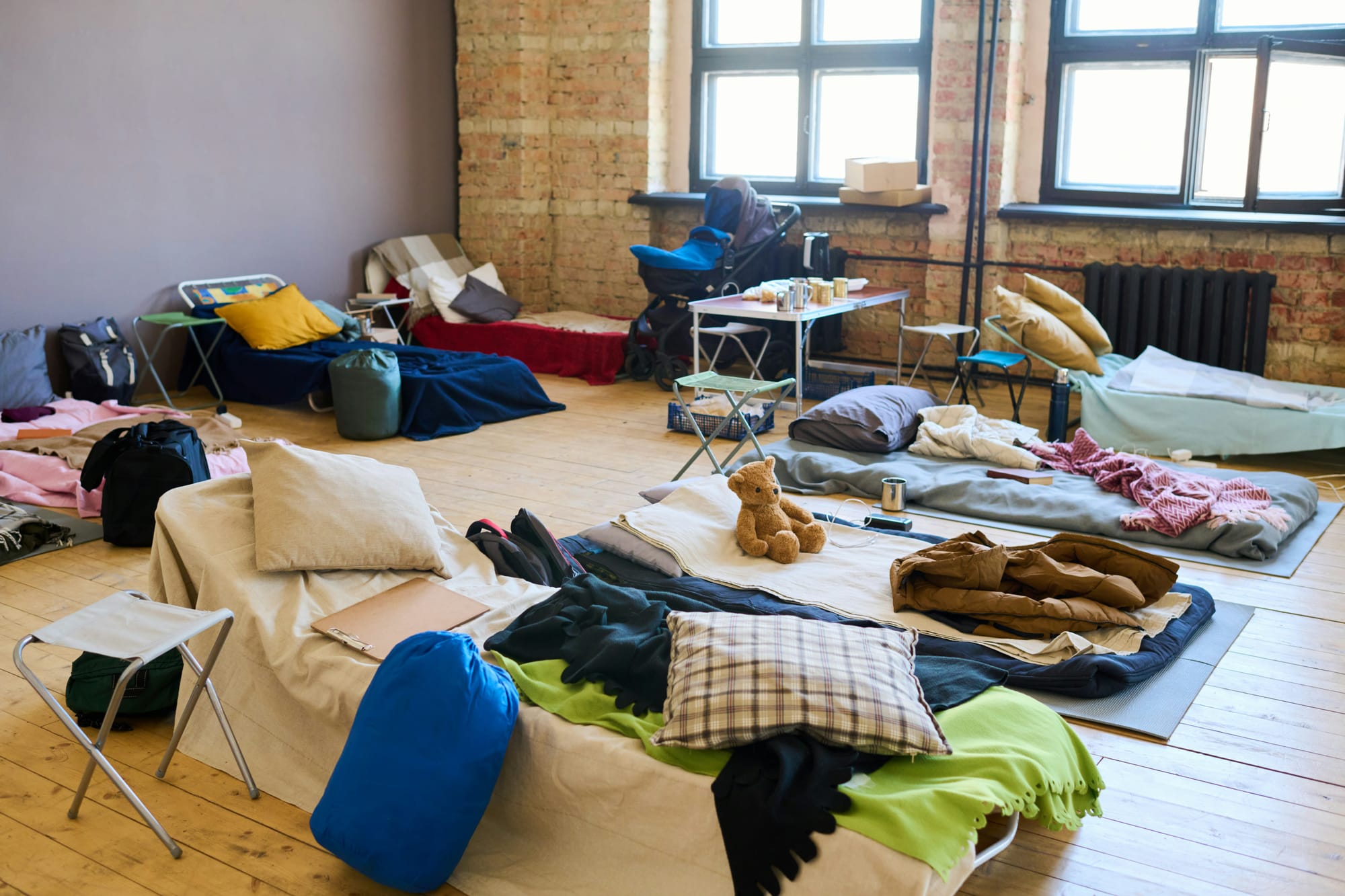 Cots, sleeping, pads, bedding, and various personal items arranged fairly neatly in a room.