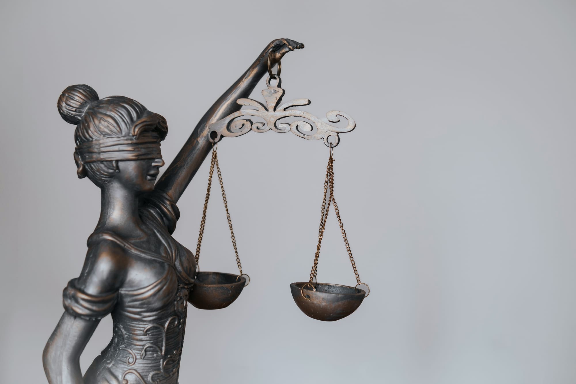A metal sculpture of Lady Justice holding a scale.