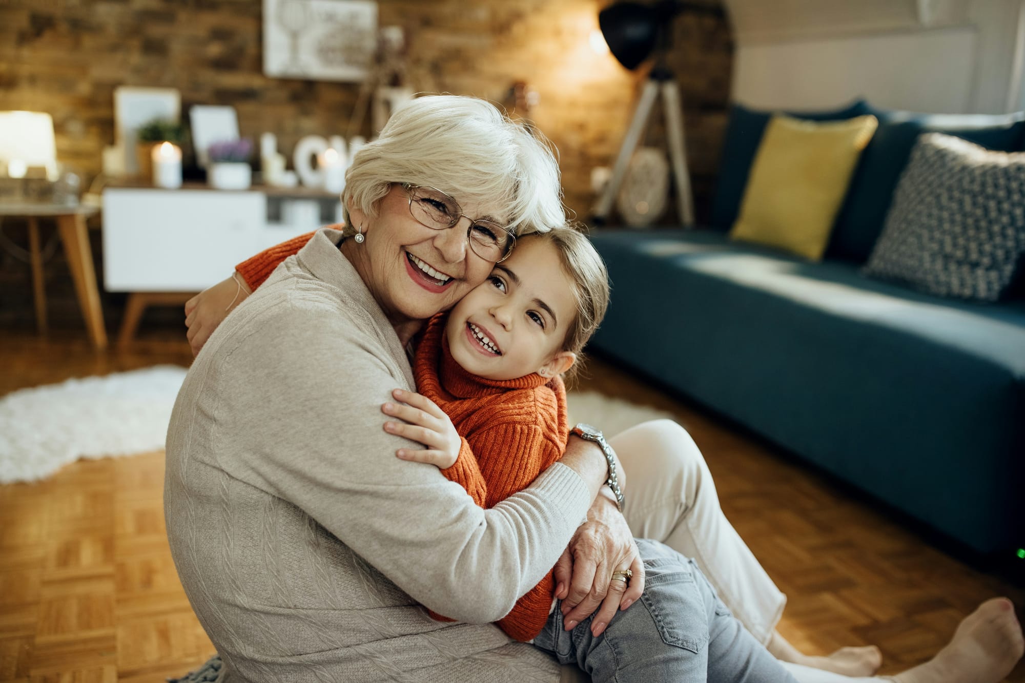 A grandmother hugs her granddaughter. Both are smiling.