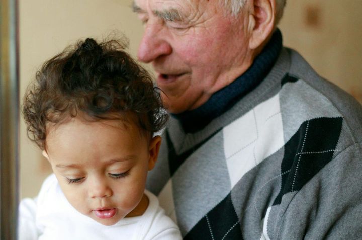 An older man with a toddler on his lap. Both have contented expressions.