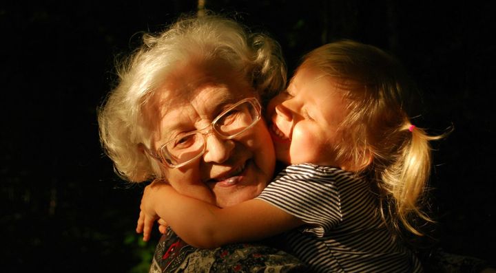 Close-up of a toddler giving her grandma a tight hug. 