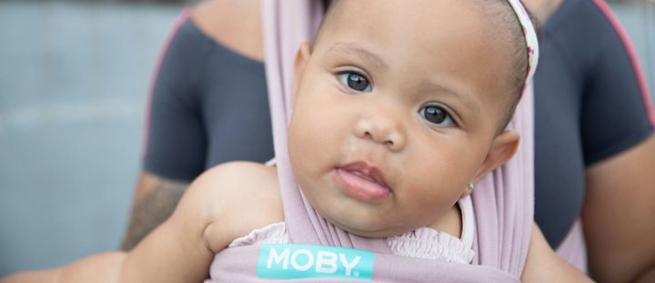 A baby looks out at the world from her baby sling. 