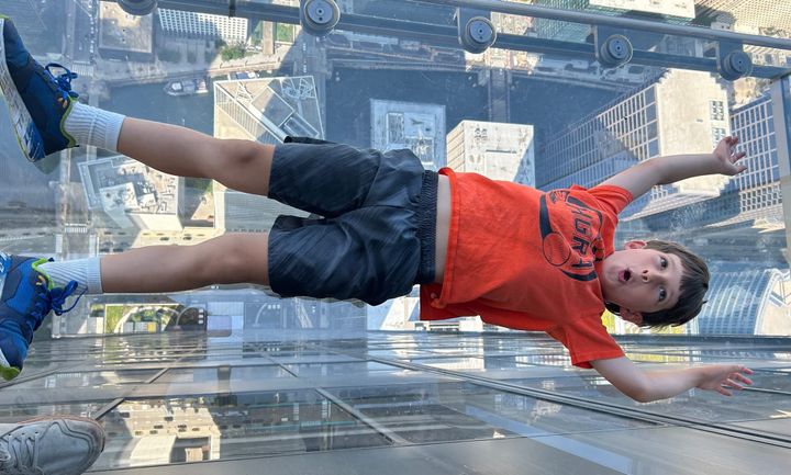Child lying on plexiglass floor of the Skydeck, Willis Tower, Chicago, pretending to fall 1600' to the ground below.