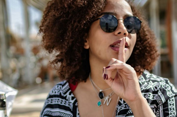 A woman puts a finger to her lips in a "shhh" motion. 