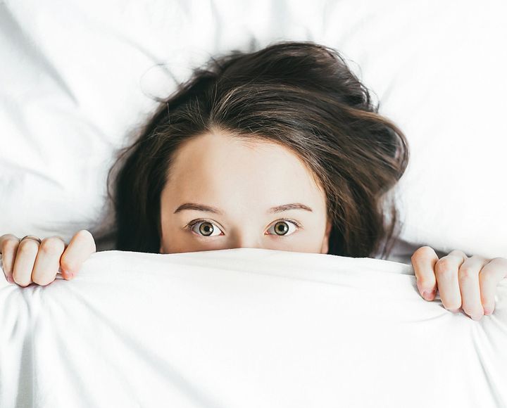 A teen tucked between sheets pulled up to her wide-open eyes. 