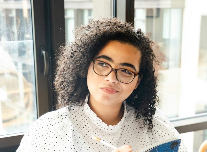 A teen considers a thought, maybe, by her expression, with a bit of mischief in mind.