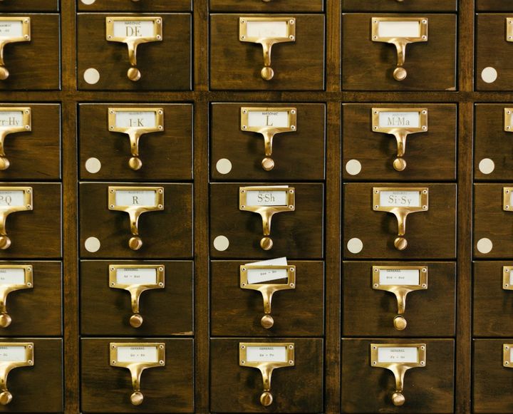 Close-up of drawers in a wooden file cabinet labeled alphabetically.