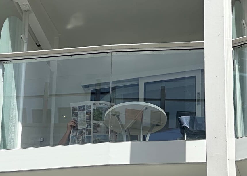 A man reads a newspaper from his balcony