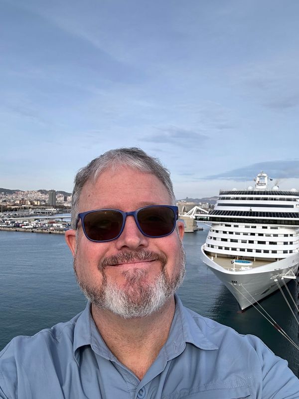 A man poses in front of a cruise ship in Barcelona