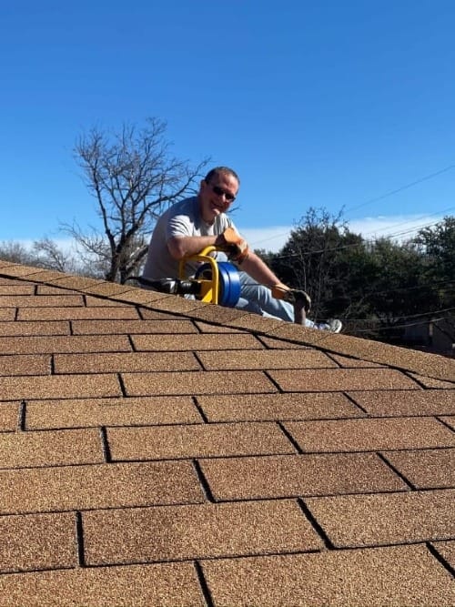 Bryan using a drain snake on our roof - one of many DIY maintenance tasks we handle to save on our freedom number.