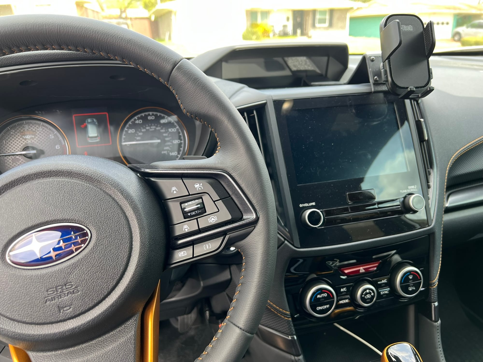 Interior dashboard view of Subaru with newly installed phone mount, steering wheel with Subaru logo, and digital display visible.