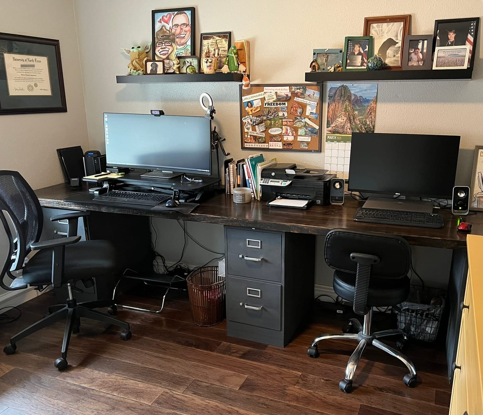 Home office with dual desk setup, personal photos on wall shelves, a vision board with "FREEDOM" visible, and various personal items that will need to be removed for home staging.